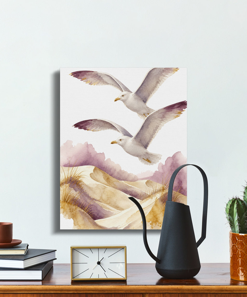 Watercolor painting of two gulls flying over sand dunes with purple clouds.