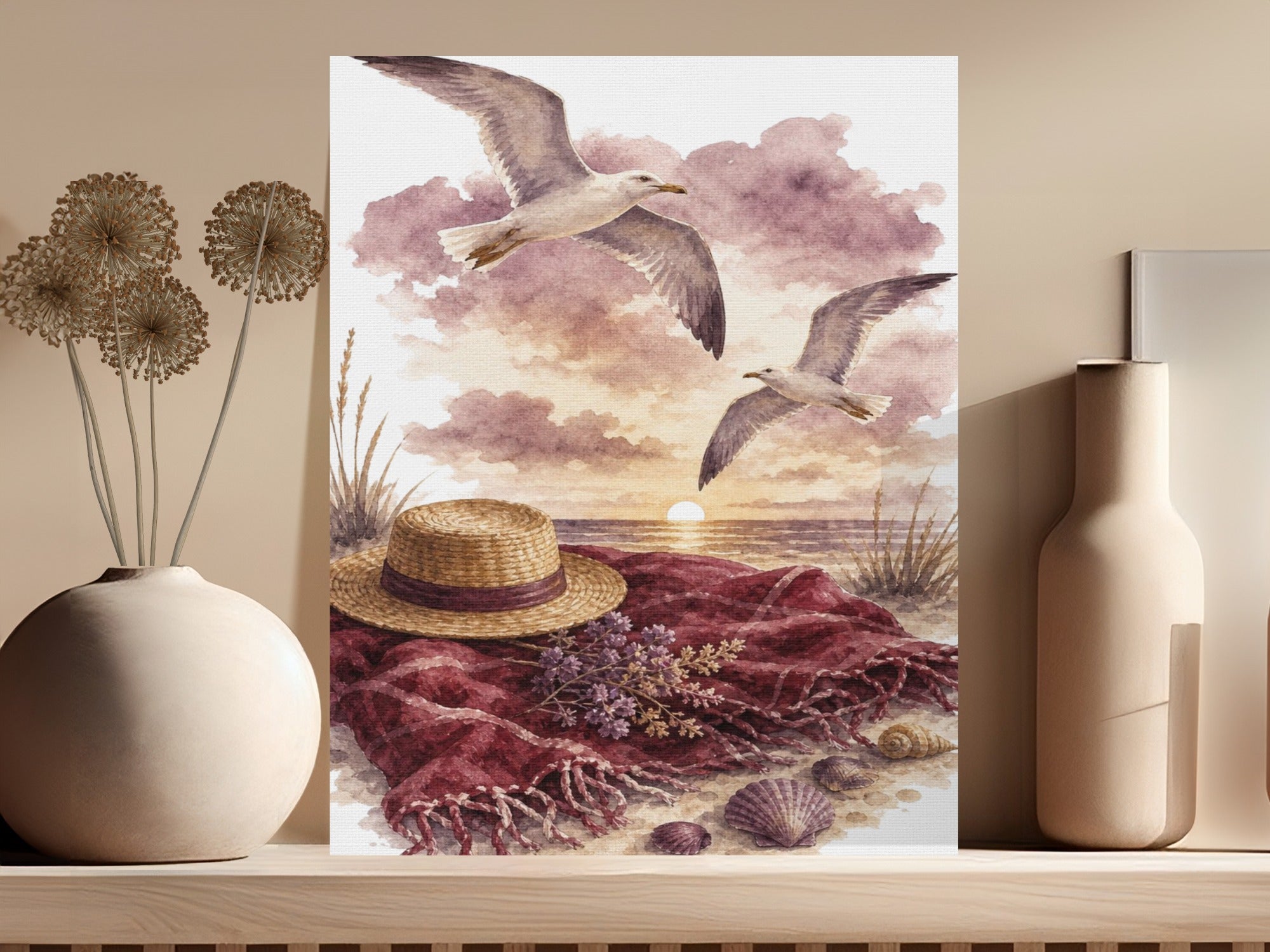 Watercolor painting of two seagulls flying over a beach scene with a hat and blanket.