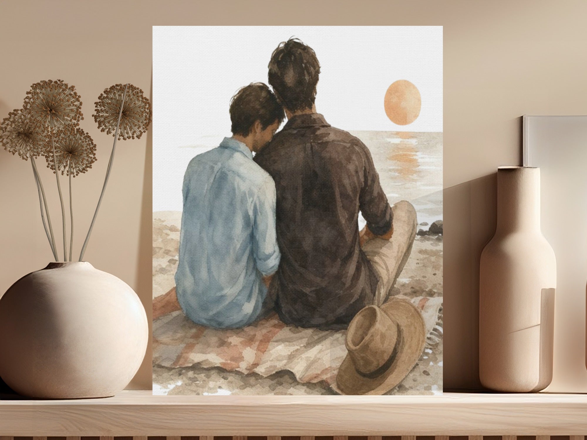 Two people sit on a blanket at the beach watching the sunset.