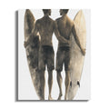 Two men with surfboards stand with arms around each other.