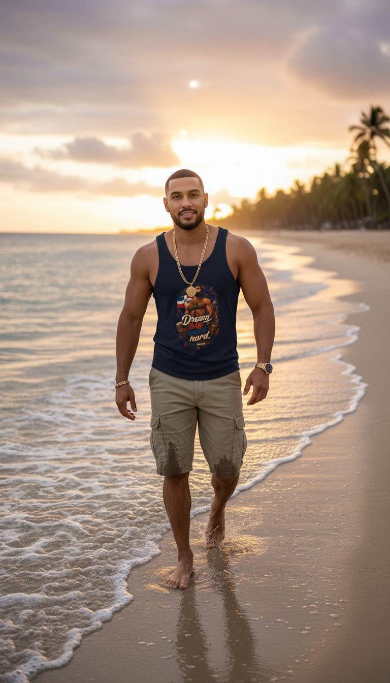 Oso Caribeño navy graphic tank top with Dream Big Dominican heritage design worn by a man walking on a beach at sunset