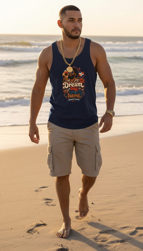Oso Caribeño navy blue tank top with Dream Big Dominican heritage graphic on a man walking on the beach at sunset.