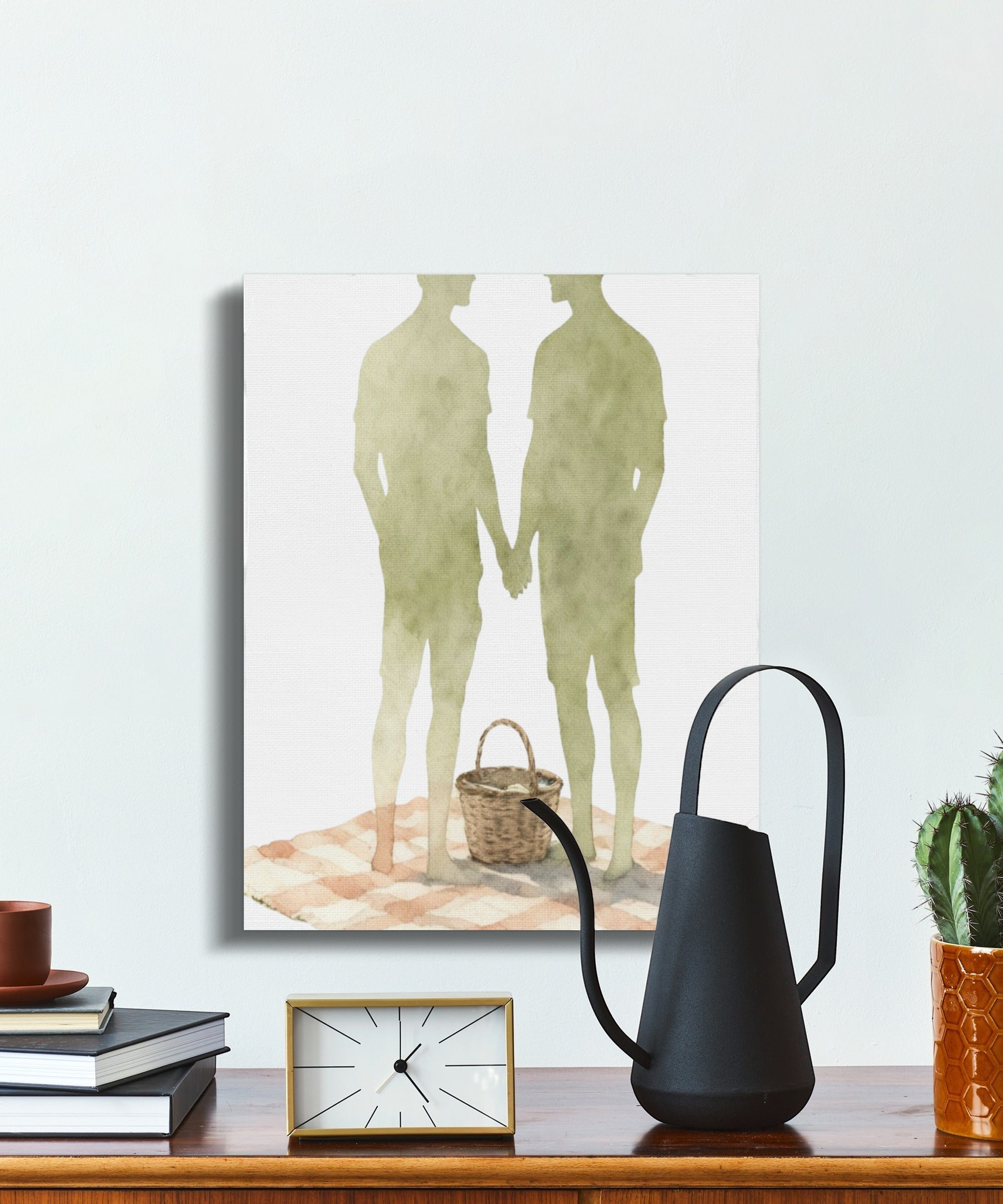 Oso Caribeño watercolor canvas print featuring two men holding hands at a picnic, displayed on a white wall.