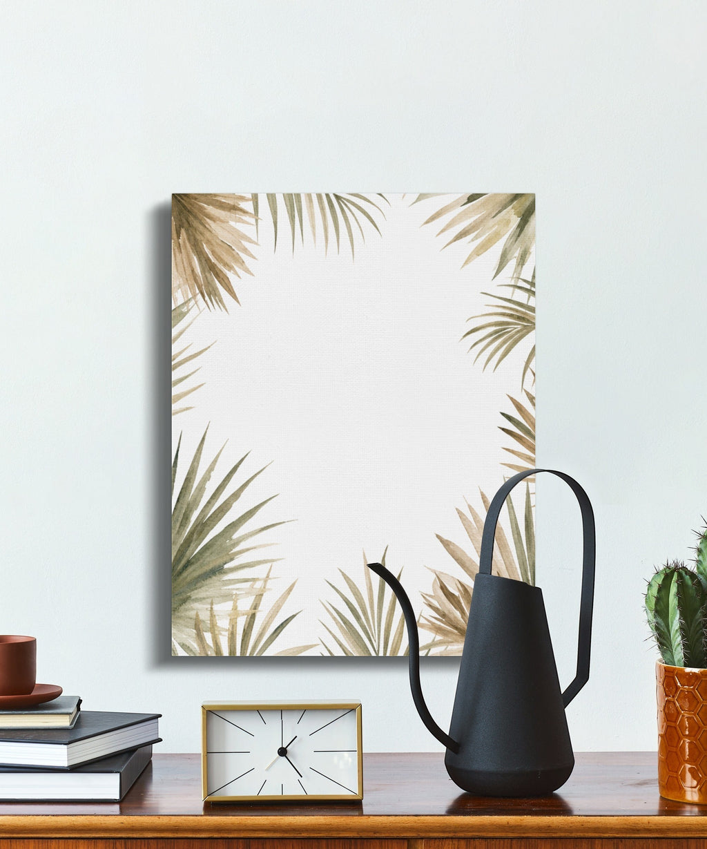 Oso Caribeño watercolor palm frond canvas art with earthy tones on a desk with a black watering can and cactus.